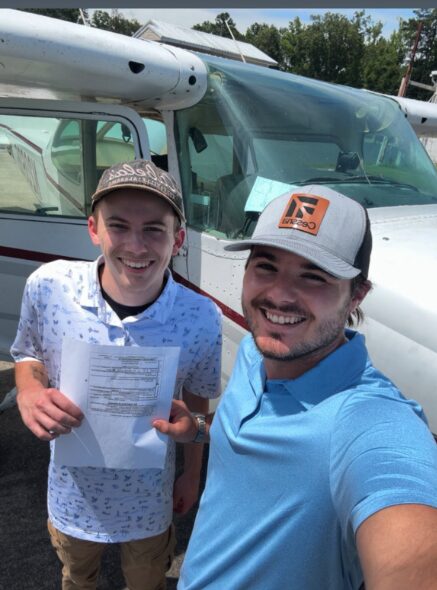 Blackstone Aviation instructor and student holding a completed training document by the aircraft